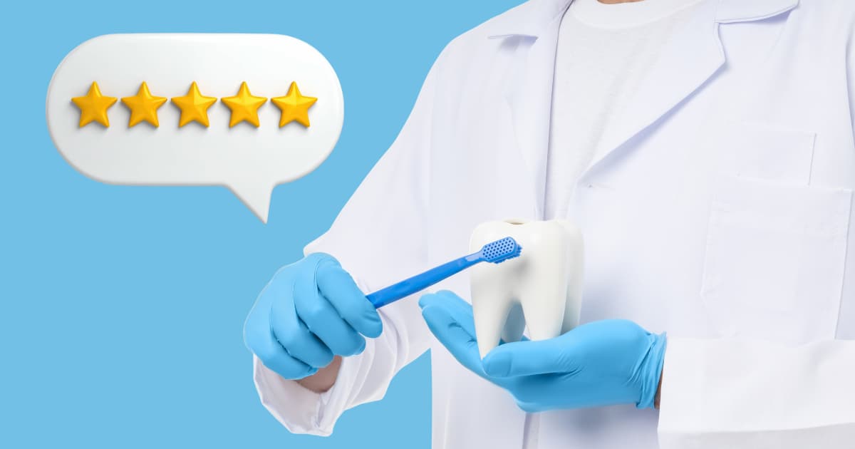 dentist in white coat holding a large display tooth, showing how to brush while 5 stars indicating a review are in a bubble in the upper left corner