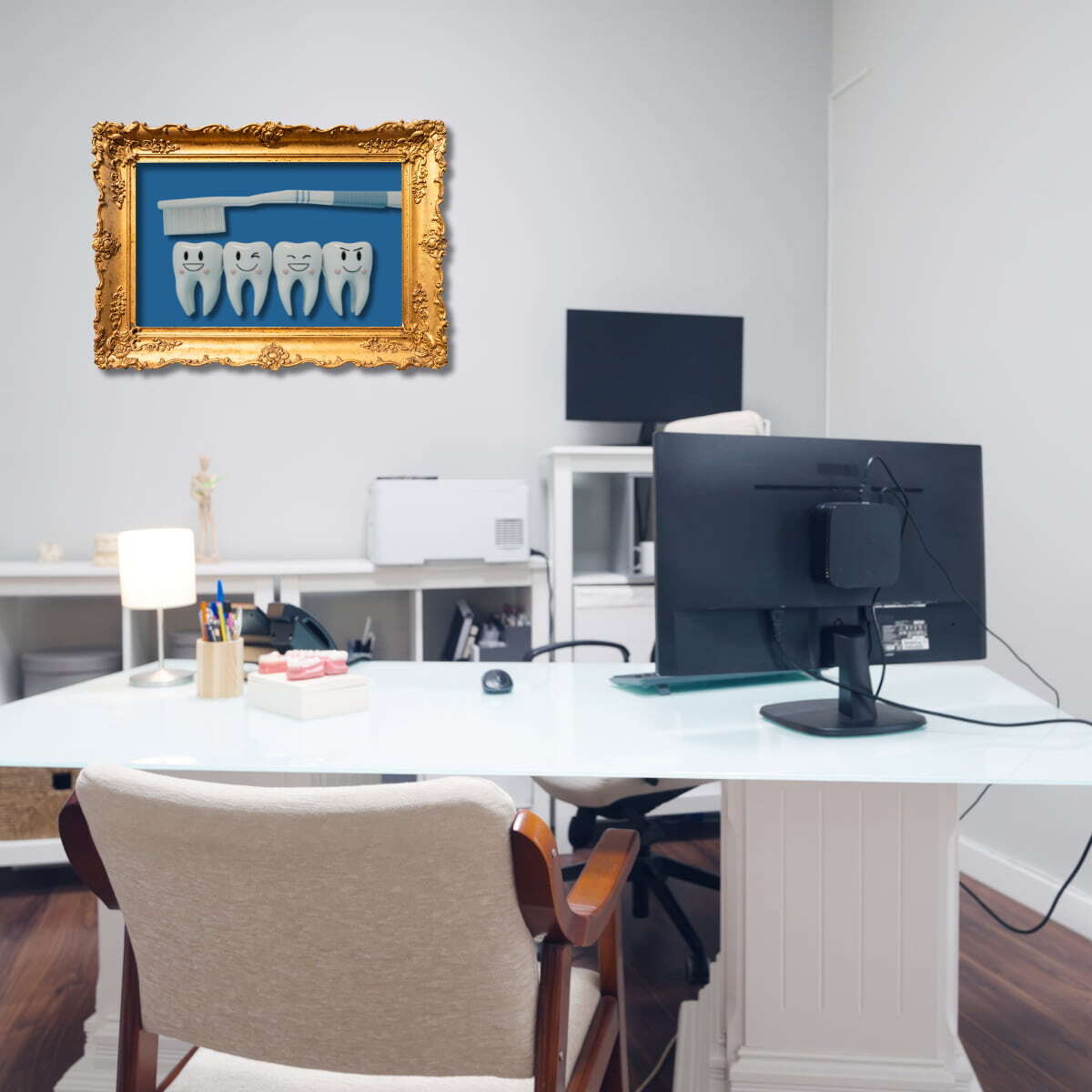 dentist personal office with a white desk, a computer monitor and a framed photo of teeth and a toothbrush on the wall