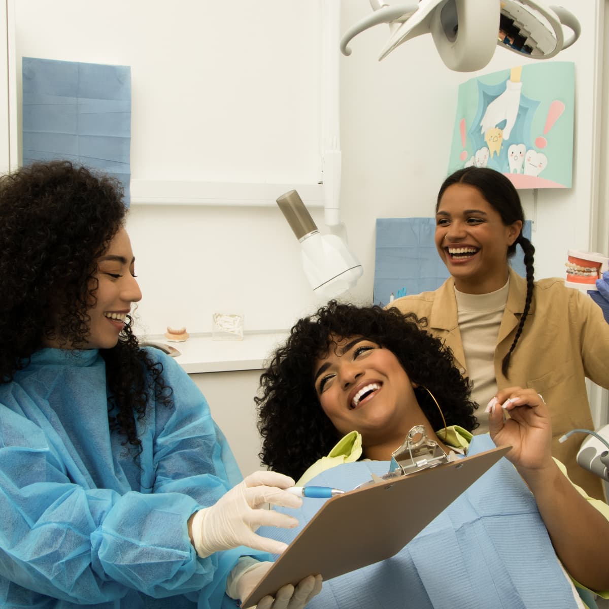 a black dentist talks to a black patient about treatment plans while a woman with dark brown braided hair looks on